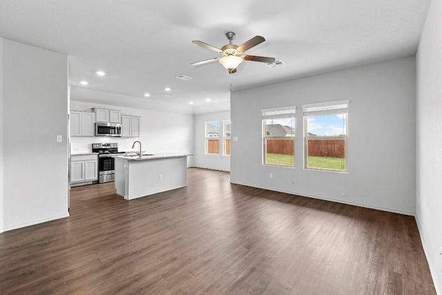 unfurnished living room with dark wood-style floors, a sink, visible vents, recessed lighting, and ceiling fan
