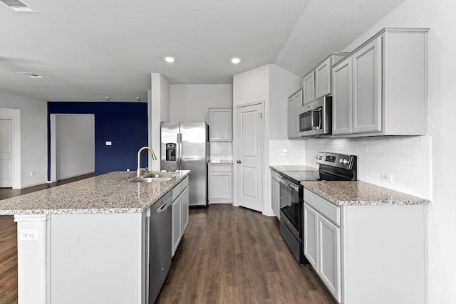 kitchen featuring a sink, dark wood-style flooring, decorative backsplash, light stone countertops, and appliances with stainless steel finishes