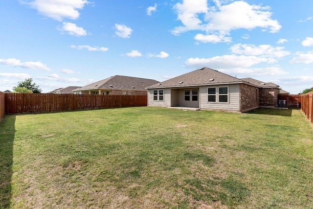 rear view of house featuring a yard and a fenced backyard