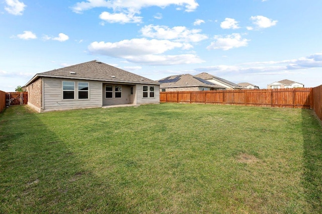 rear view of house featuring a fenced backyard and a lawn