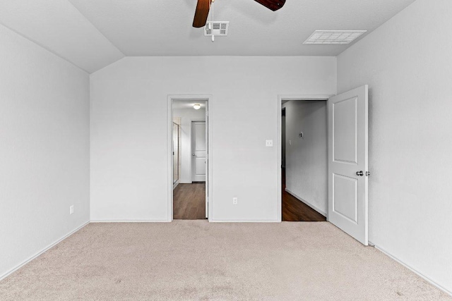 unfurnished bedroom with carpet floors, visible vents, lofted ceiling, and baseboards