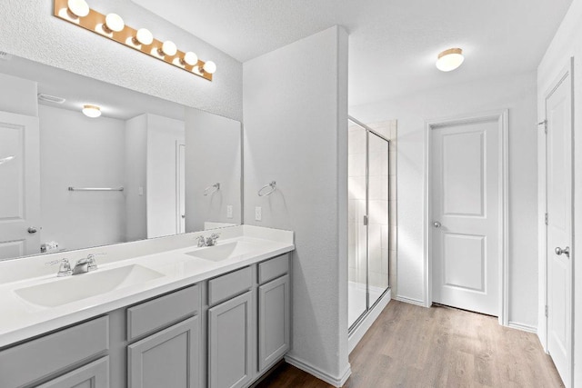 full bath featuring wood finished floors, a sink, and a stall shower