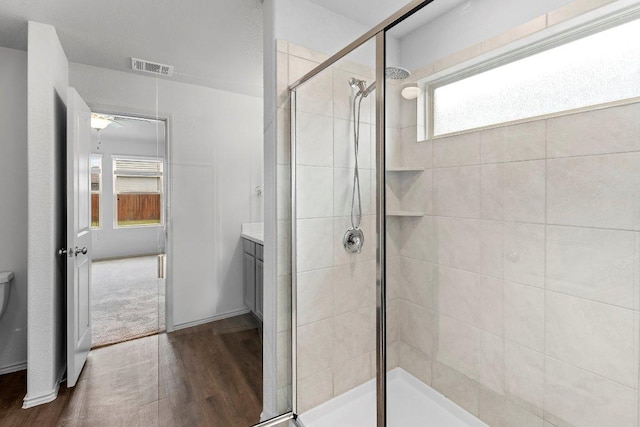 bathroom with a shower stall, wood finished floors, visible vents, toilet, and vanity