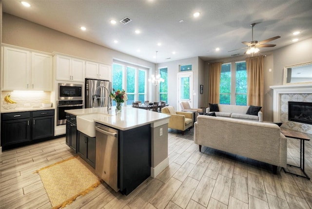 kitchen featuring white cabinetry, dark cabinets, visible vents, stainless steel appliances, and light countertops