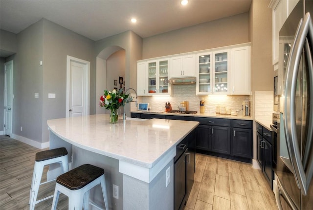 kitchen with a breakfast bar area, white cabinets, appliances with stainless steel finishes, and under cabinet range hood