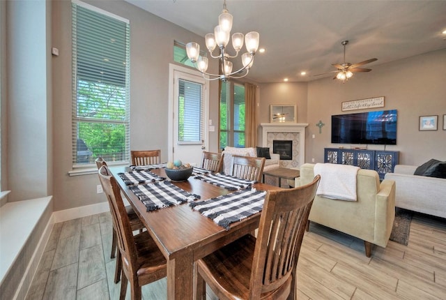 dining space with light wood-style flooring, a wealth of natural light, and ceiling fan with notable chandelier