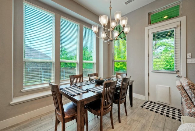 dining room with baseboards, light wood-type flooring, visible vents, and a chandelier
