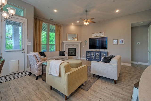 living room featuring a fireplace, recessed lighting, ceiling fan with notable chandelier, and light wood-type flooring