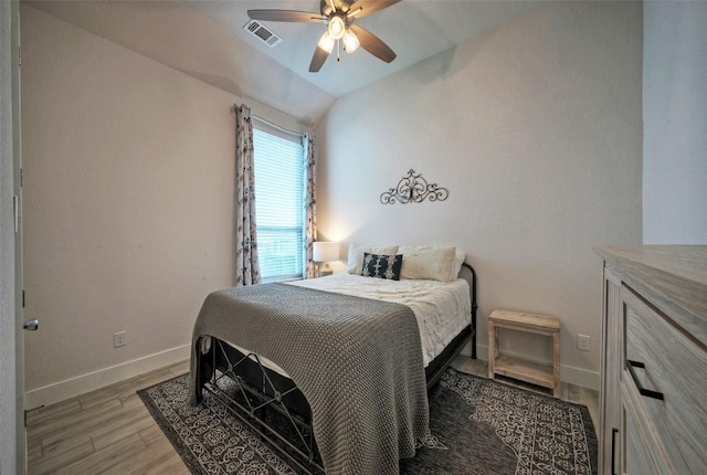 bedroom featuring lofted ceiling, visible vents, baseboards, light wood-type flooring, and a ceiling fan
