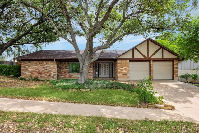 view of front facade featuring brick siding, a garage, driveway, french doors, and a front lawn