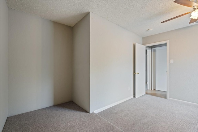 spare room featuring light colored carpet, a ceiling fan, and a textured ceiling