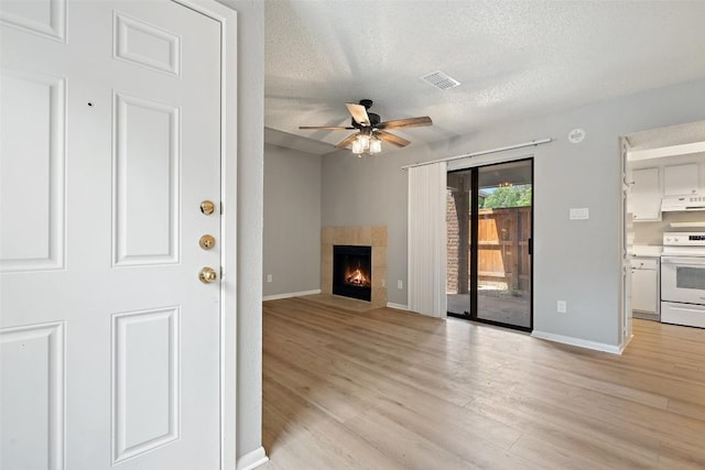 unfurnished living room with light wood-type flooring, baseboards, visible vents, a ceiling fan, and a textured ceiling