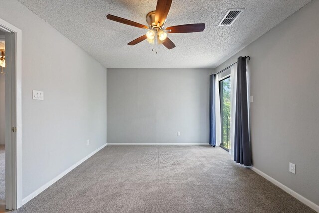 carpeted empty room featuring baseboards, visible vents, a ceiling fan, and a textured ceiling