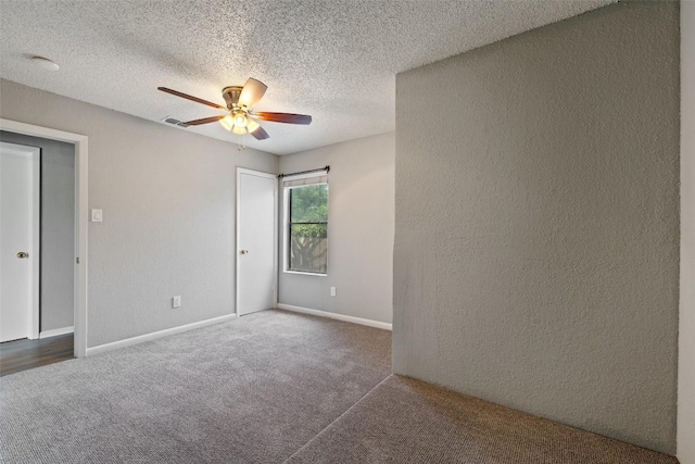 carpeted spare room with a ceiling fan, a textured wall, a textured ceiling, and baseboards