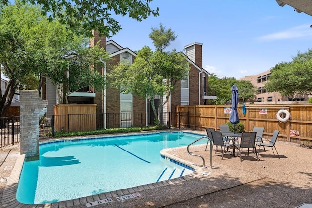 community pool with a patio and fence