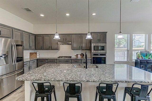 1801 Lakeside Ranch Rd, Georgetown, TX 78633 - kitchen with appliances with stainless steel finishes, a sink, recessed lighting, dark brown cabinets, and light stone countertops