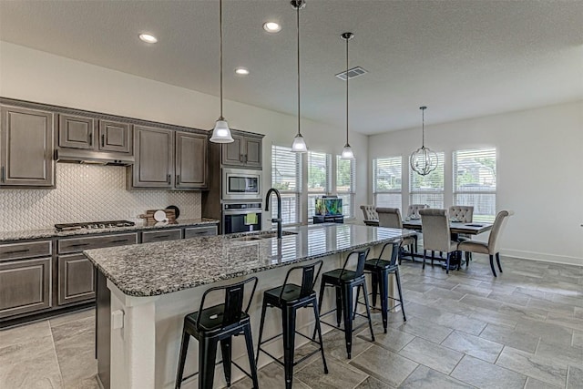 1801 Lakeside Ranch Rd, Georgetown, TX 78633 - kitchen featuring a sink, appliances with stainless steel finishes, dark stone counters, decorative backsplash, and baseboards
