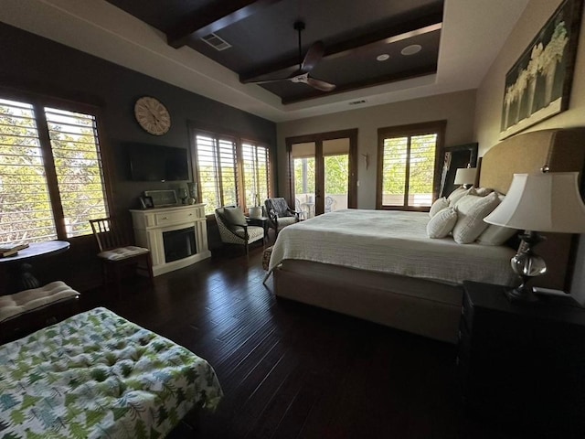 bedroom featuring dark wood-type flooring, a raised ceiling, visible vents, and multiple windows