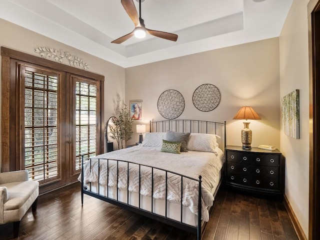 bedroom with hardwood / wood-style floors, access to outside, ceiling fan, baseboards, and a raised ceiling