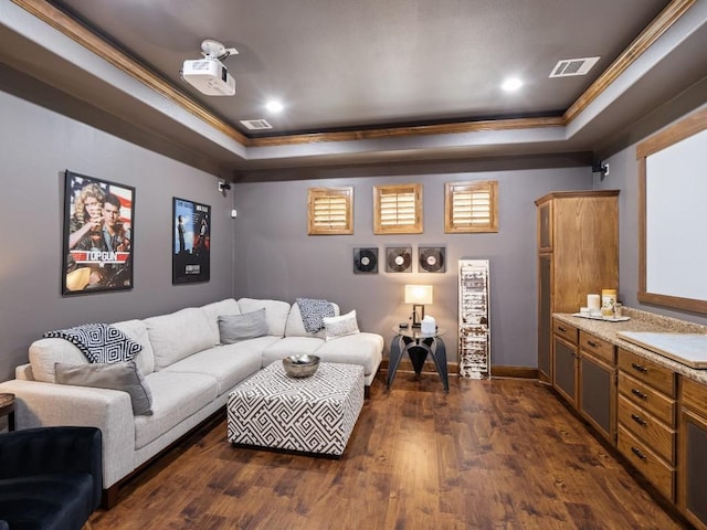 cinema room featuring crown molding, dark wood-style flooring, a raised ceiling, and visible vents
