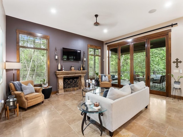 living area featuring a fireplace, a wealth of natural light, a ceiling fan, and baseboards