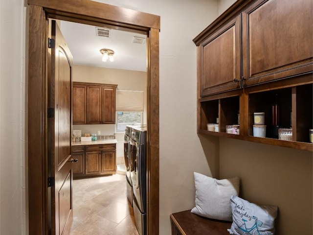 interior space featuring light tile patterned floors, washer and dryer, visible vents, and cabinet space