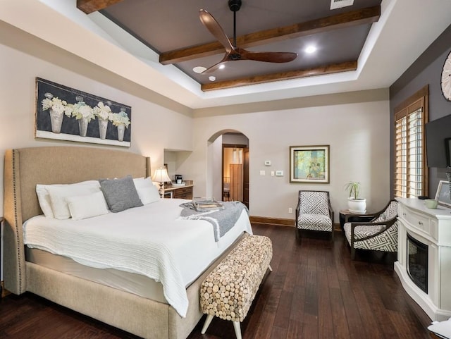 bedroom with a raised ceiling, hardwood / wood-style flooring, baseboards, and arched walkways