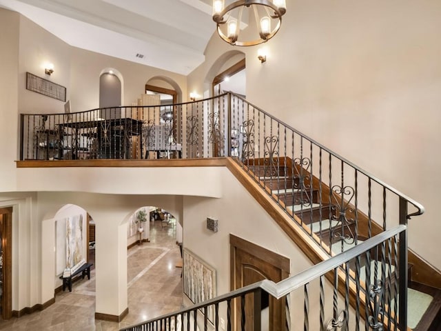 2749 Springwood Ln, Georgetown, TX 78628 - staircase with a high ceiling, arched walkways, and a chandelier