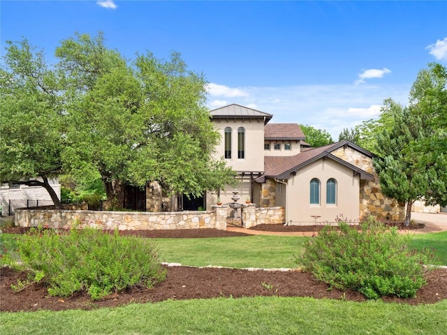 rear view of property with stucco siding, a yard, and stone siding