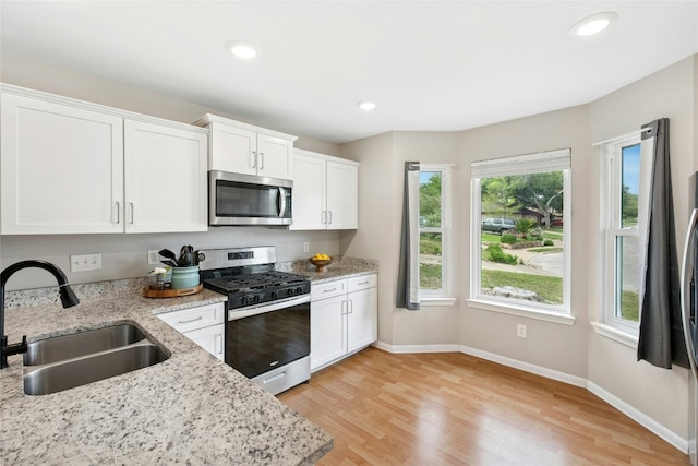 kitchen with white cabinetry, light wood-style floors, appliances with stainless steel finishes, and a sink