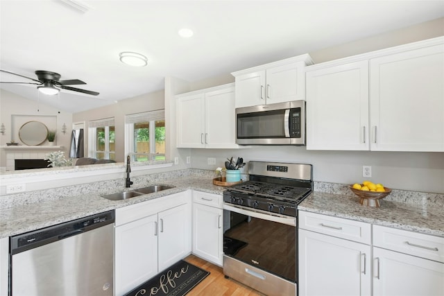 kitchen featuring light wood-style flooring, appliances with stainless steel finishes, a sink, white cabinetry, and a ceiling fan