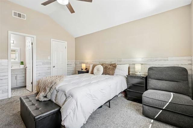 bedroom with lofted ceiling, visible vents, a wainscoted wall, and carpet floors