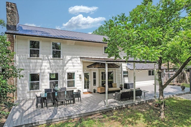 back of property with central air condition unit, metal roof, a wooden deck, a chimney, and outdoor lounge area
