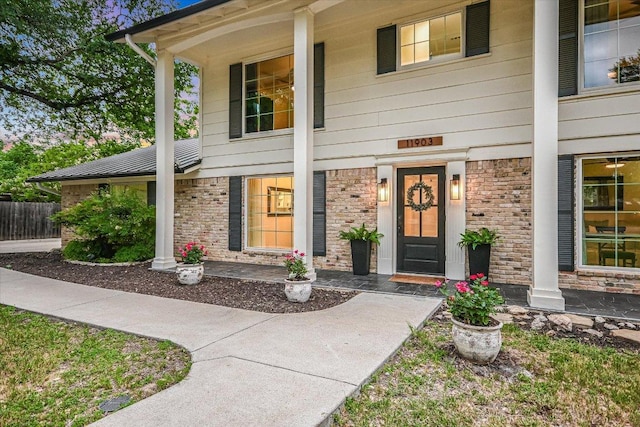 property entrance with fence and brick siding