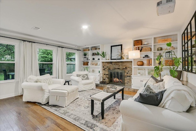 living area featuring light wood-style floors, a fireplace, visible vents, and plenty of natural light