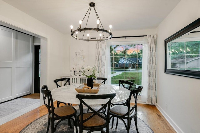 dining room with light wood finished floors, a notable chandelier, and baseboards