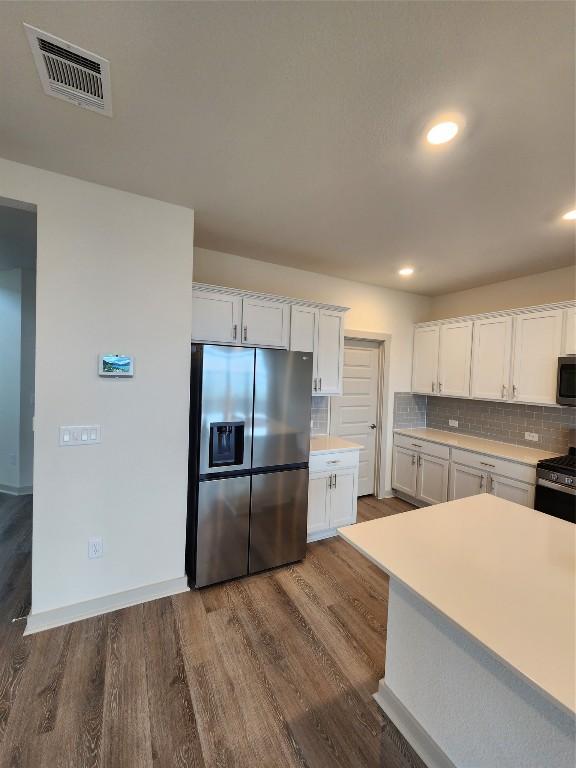 7500 Traylor Cv, Austin, TX 78724 - kitchen with stainless steel appliances, white cabinetry, wood finished floors, light countertops, and backsplash