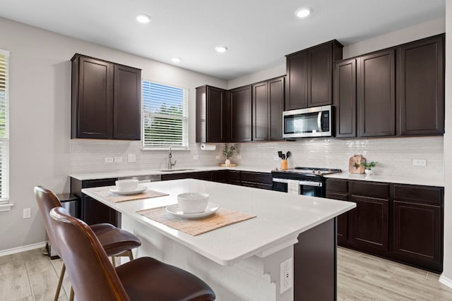 330 Conestoga Dr, Kyle, TX 78640 - kitchen featuring stainless steel appliances, a breakfast bar, light countertops, decorative backsplash, and recessed lighting