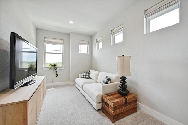 living area featuring light colored carpet and baseboards
