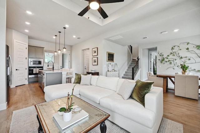 living area featuring recessed lighting, ceiling fan, stairway, and light wood-style flooring