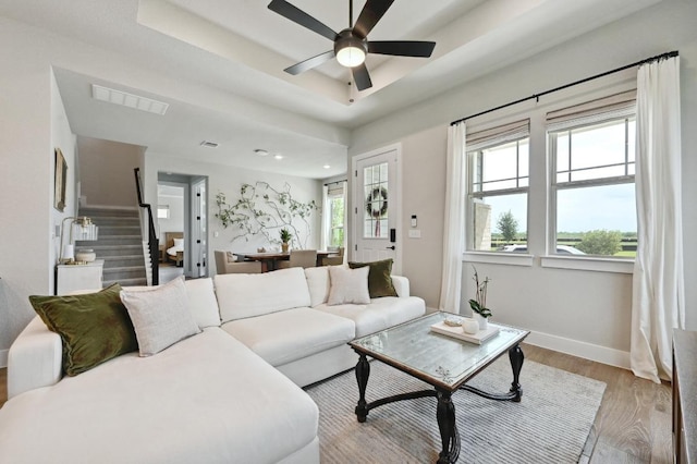 living area featuring stairway, ceiling fan, visible vents, baseboards, and wood finished floors