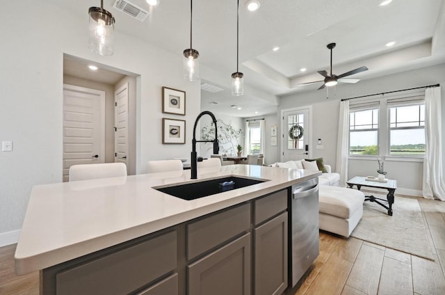 kitchen featuring a sink, gray cabinets, a tray ceiling, visible vents, and open floor plan