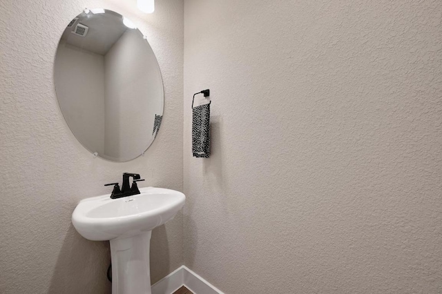 bathroom featuring a textured wall and a sink
