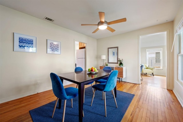 dining space with baseboards, visible vents, ceiling fan, and light wood finished floors