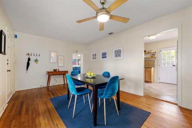 dining space featuring light wood finished floors, a ceiling fan, and visible vents