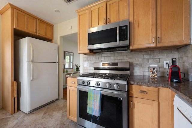 kitchen with tasteful backsplash, appliances with stainless steel finishes, and dark stone counters