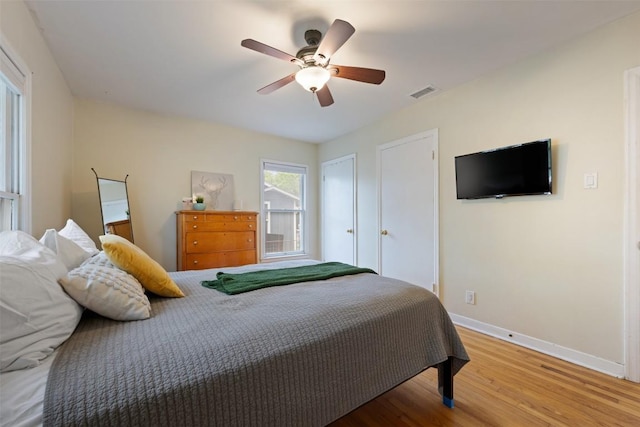 bedroom with baseboards, visible vents, wood finished floors, and a ceiling fan