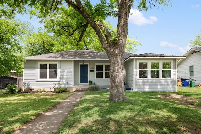 ranch-style home with a front yard and roof with shingles