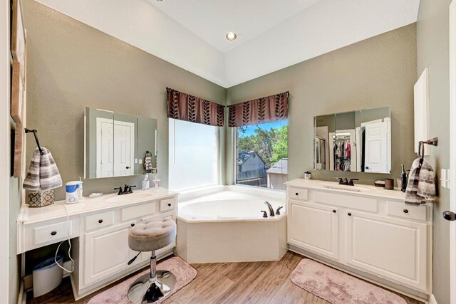 8236 Phantom Canyon Dr, Austin, TX 78726 - full bathroom featuring wood finished floors, a bath, and two vanities
