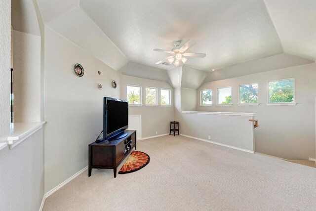interior space featuring ceiling fan, visible vents, baseboards, vaulted ceiling, and light carpet